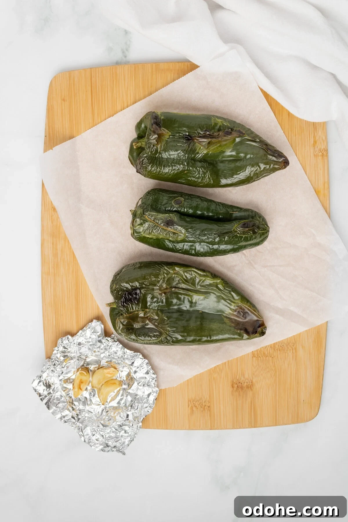 An overhead image of the roasted poblano peppers on a chopping board.