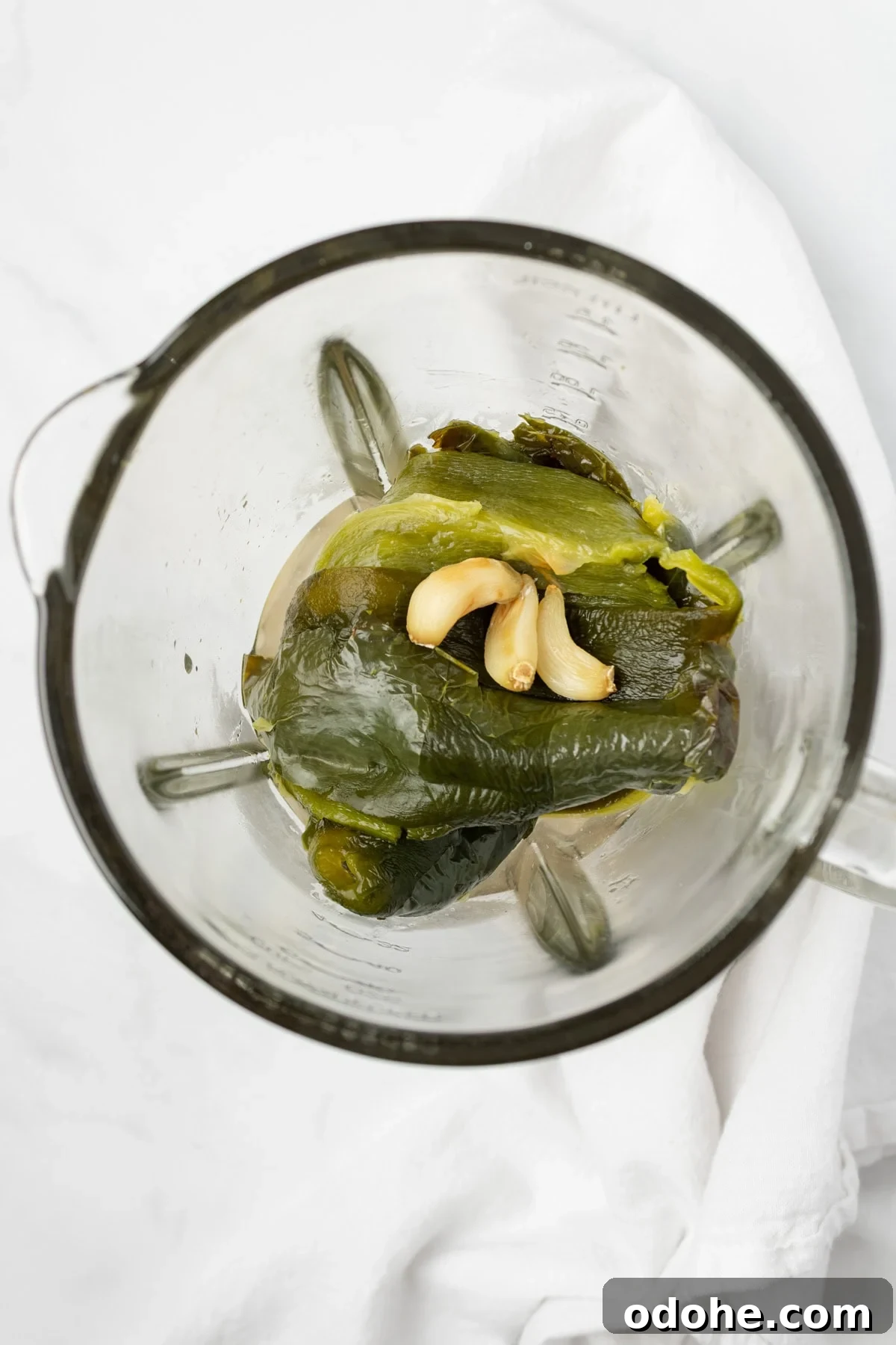 An overhead image of adding the poblano peppers and garlic to the blender.