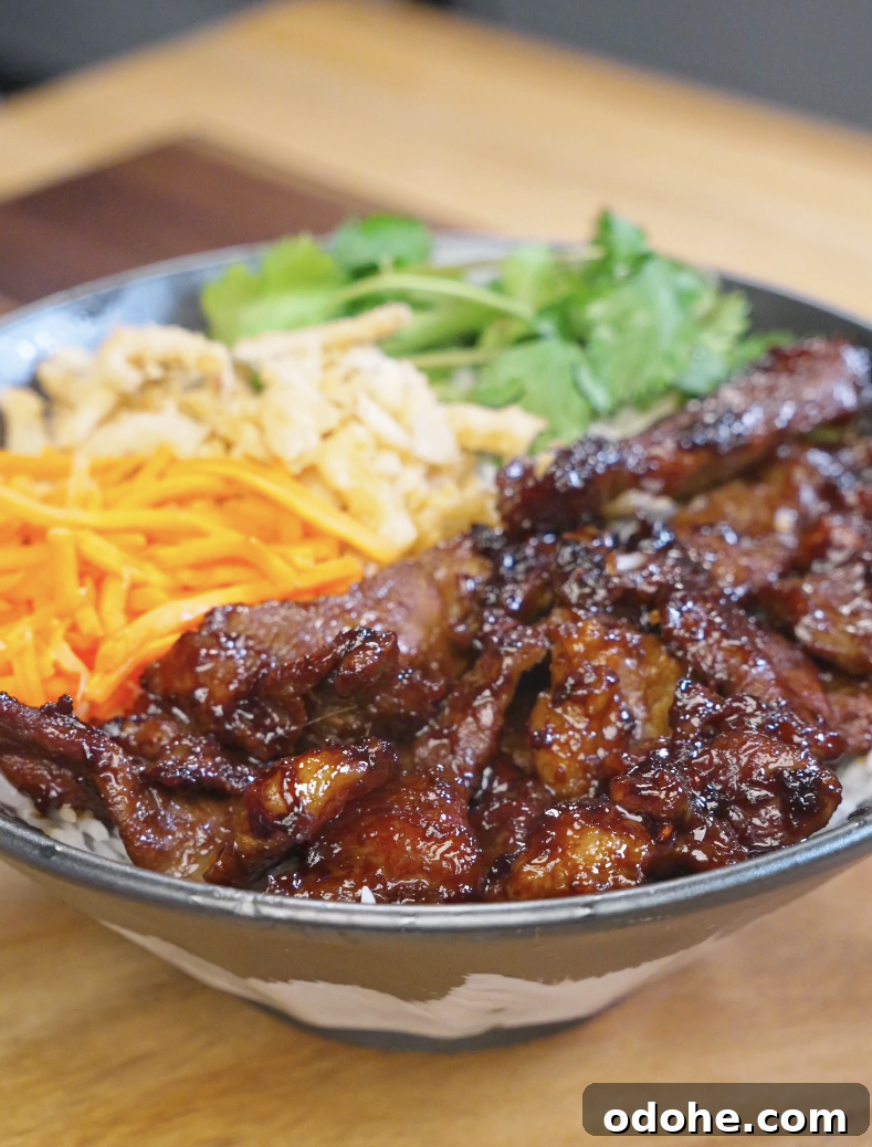 Bowl of Vietnamese-inspired lemongrass beef served over steamed rice with fresh cilantro, shredded carrots, and crispy onions for a flavorful and balanced weeknight dinner.