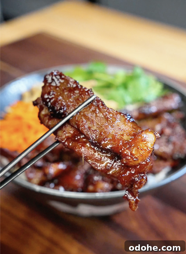 Close-up of caramelized lemongrass beef held with chopsticks showing the glossy savory glaze and tender texture in this quick and easy Lemongrass Beef Recipe.