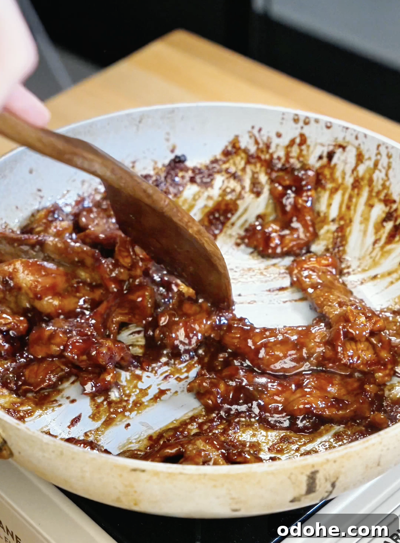 Thinly sliced lemongrass beef caramelizing in a pan with a glossy soy and fish sauce glaze as the sauce thickens around the tender beef strips in this easy Lemongrass Beef Recipe.