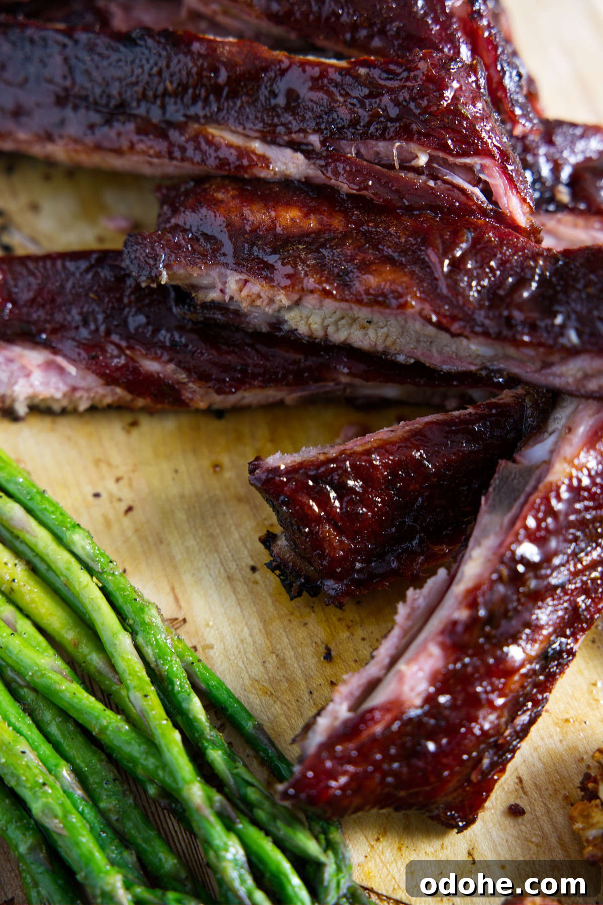 sliced traeger 3-2-1 ribs on cutting board with asparagus