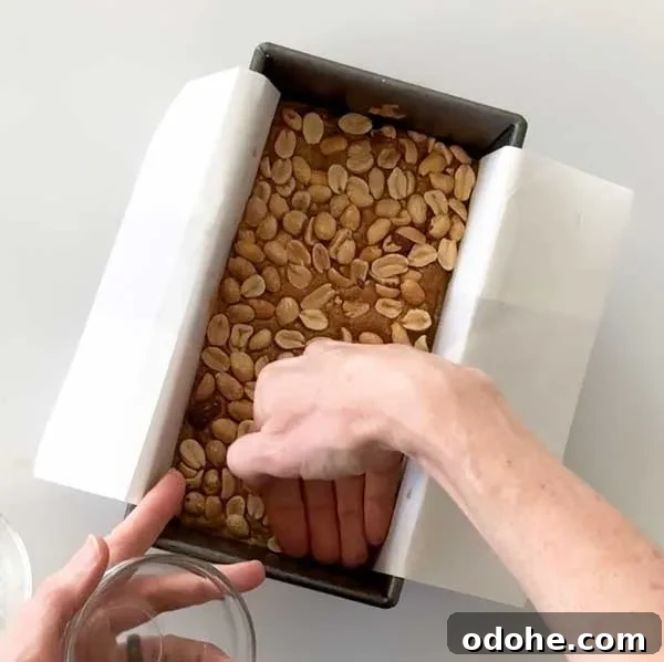 Gluten-Free Snickers Copycat Recipe: Homemade Chocolate Caramel Nougat 11 Pressing in the layer of peanuts.