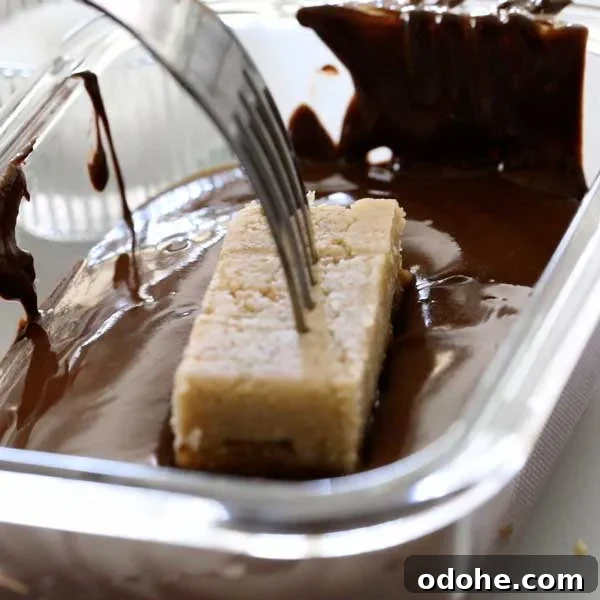 Gluten-Free Snickers Copycat Recipe: Homemade Chocolate Caramel Nougat 15 Dipping the snickers bar in the melted chocolate with a fork.