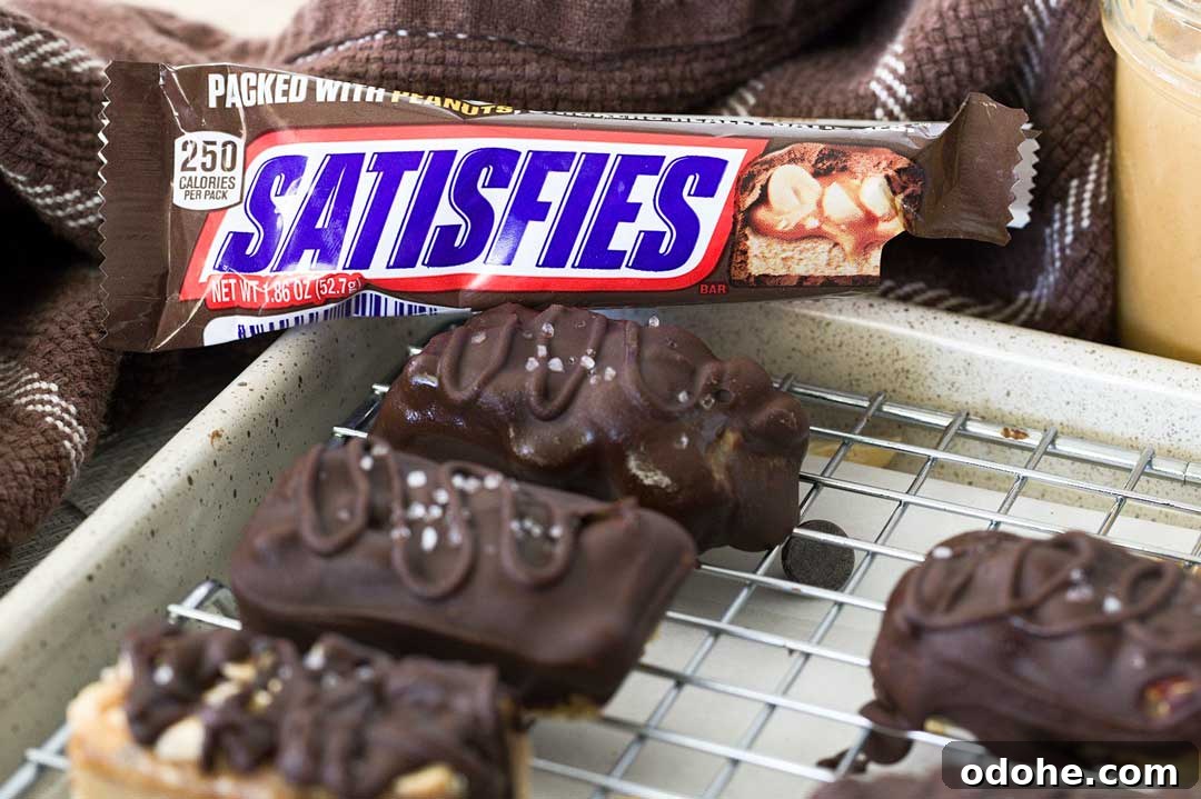 Gluten-Free Snickers Copycat Recipe: Homemade Chocolate Caramel Nougat 3 A Snickers candy bar wrapper next to several gluten-free snicker bars on a cooling rack.
