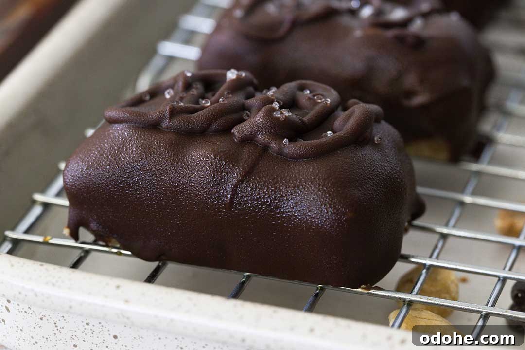 Gluten-Free Snickers Copycat Recipe: Homemade Chocolate Caramel Nougat 4 A close-up of a gluten-free Snickers bar covered in chocolate on a cooling rack.