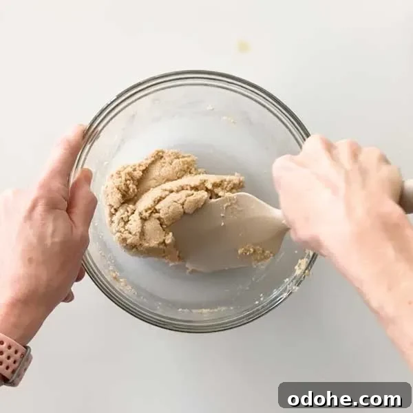 Gluten-Free Snickers Copycat Recipe: Homemade Chocolate Caramel Nougat 7 Mixing the cookie layer ingredients with a spatula in a mixing bowl.