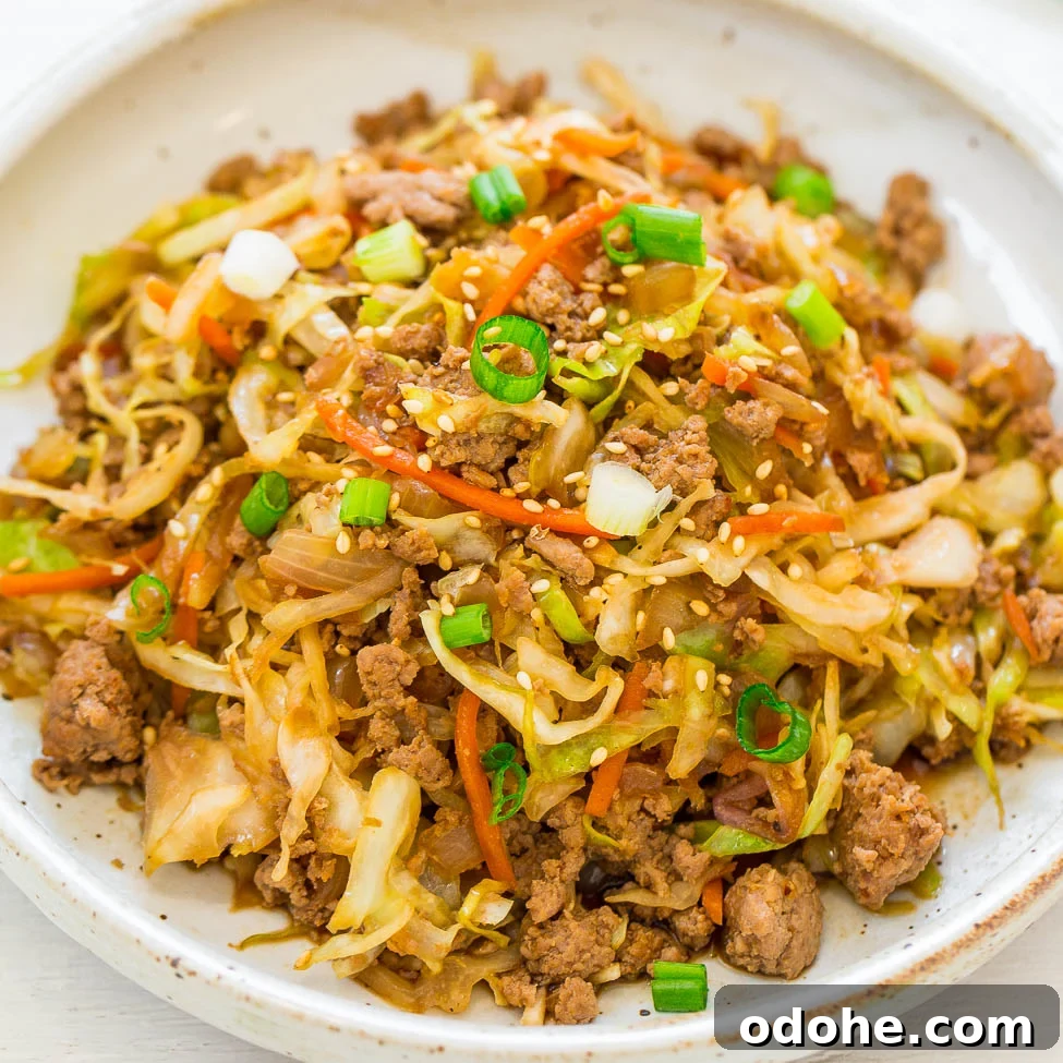 A bowl of stir-fried ground meat and vegetables garnished with green onions and sesame seeds.
