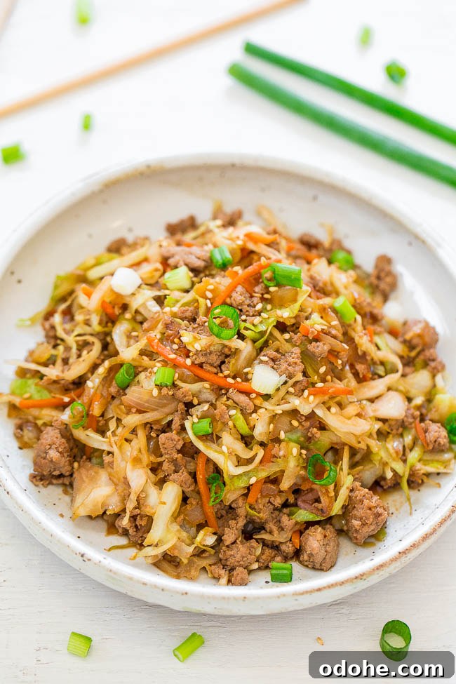 Stir-fried noodles with ground meat, shredded vegetables, and garnished with sesame seeds and sliced green onions.