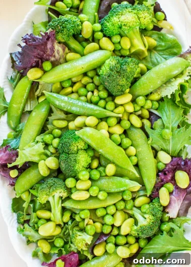 A fresh green salad with various vegetables including broccoli, peas, and leafy greens.