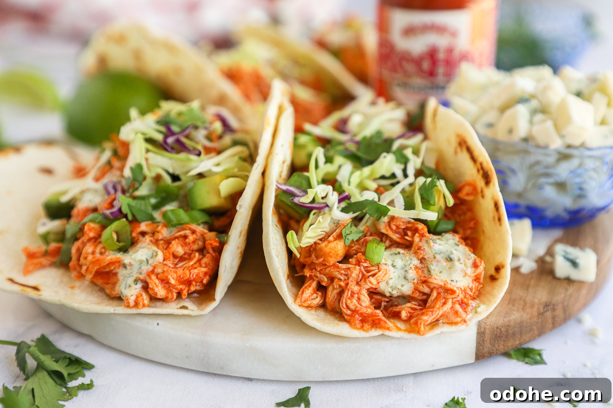 Baked Buffalo Chicken Tacos with Cilantro-Lime Crema 3 Creamy and tangy with just the right amount of heat! These delicious chicken tacos are baked in the oven and topped with fresh cabbage, cilantro and avocado!