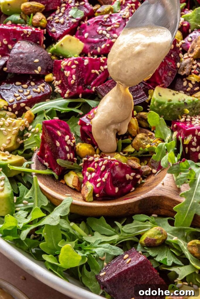 Roasted Beet Salad with Lemon Tahini Dressing and Pistachios 3 close-up of Tahini dressing being drizzled over roasted beet salad