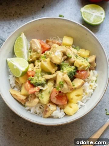 Green chicken curry with pineapple in a bowl with vegetables and a linen around it.