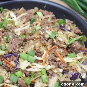 Gluten-Free Inside-Out Egg Roll Recipe: Crispy, Flavorful Wraps 12 Inside out egg roll in a skillet with green onions on top and a wooden spoon and white plates behind it.