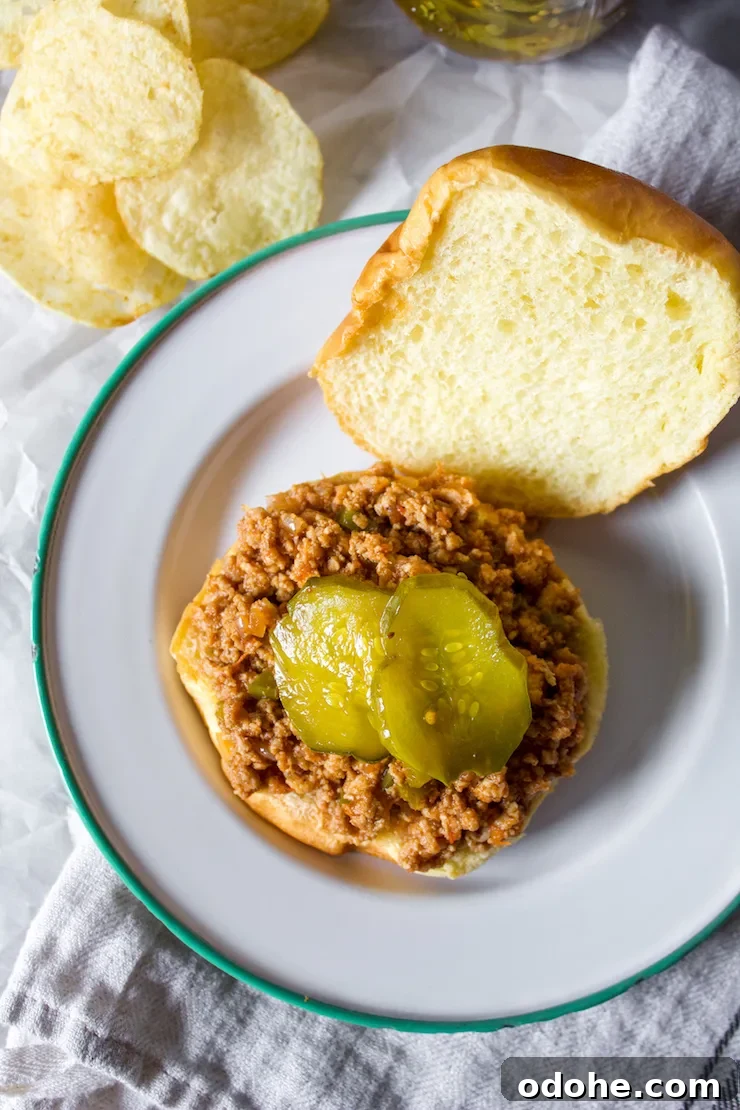 Overhead view of open faced turkey sloppy joe with pickles and potato chips