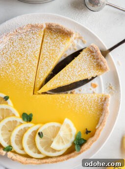 lemon curd tart garnished with lemon slices and two slices cut from tart