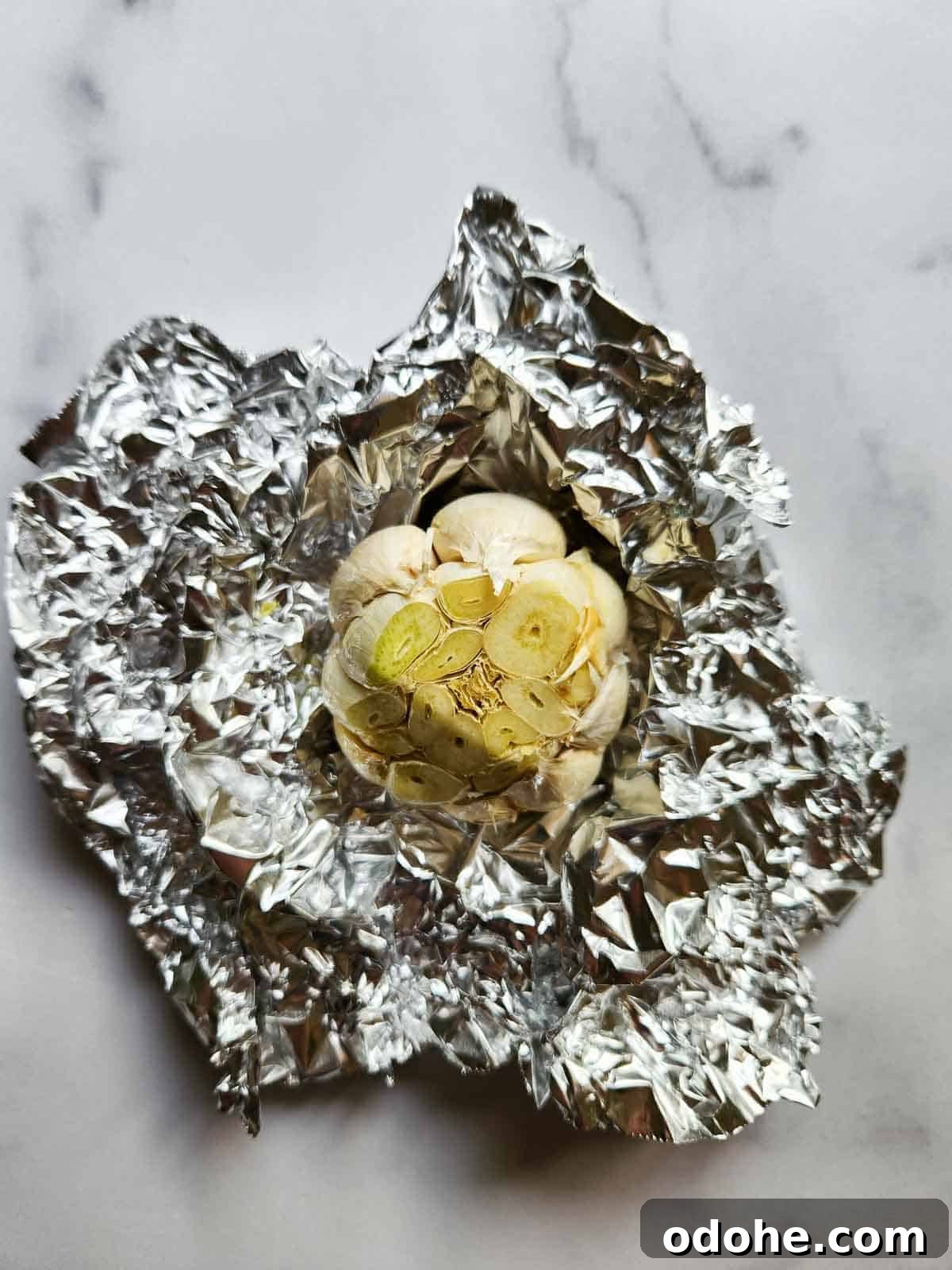 Roasted Garlic Pesto Sauce Recipe for Rich, Creamy Flavor 4 Raw garlic with top cut in aluminum foil.