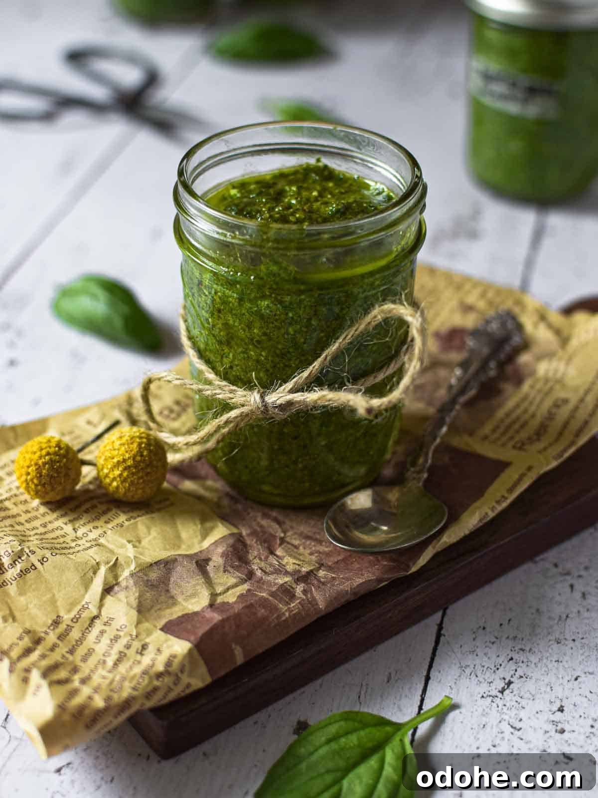 Roasted Garlic Pesto Sauce Recipe for Rich, Creamy Flavor 8 Angled view of pesto sauce in a small clear jar on a wooden surface.