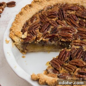 Golden crusted pecan pie with creamy filling and a slice missing, in a white pie plate.