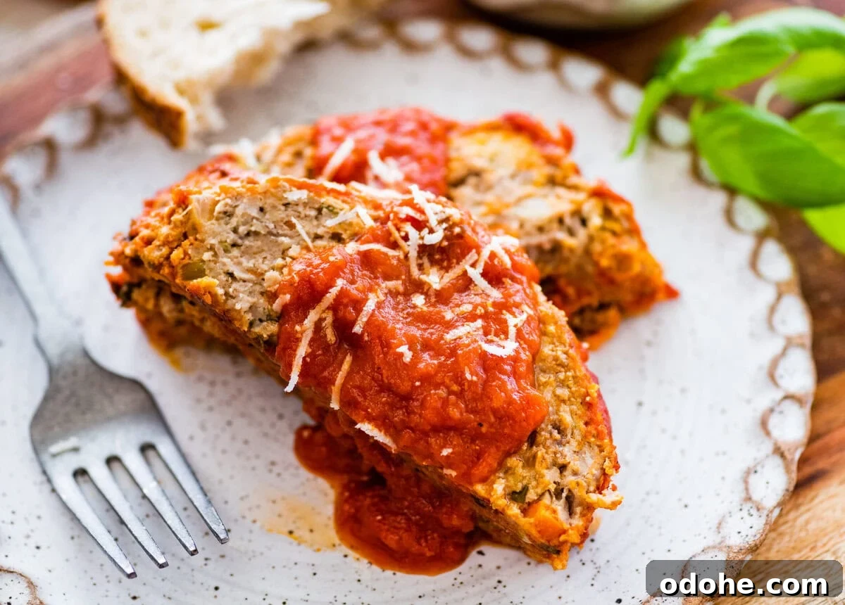 two slices of Italian meatloaf on a plate with extra sauce on top and bread on the side.
