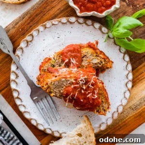 two slices of Italian meatloaf on a plate with extra sauce on top and bread on the side.