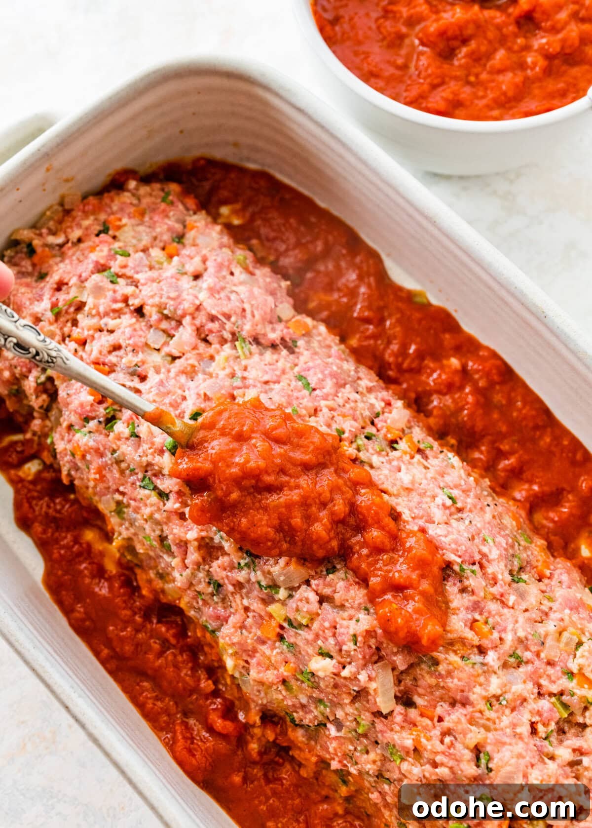 add the meatloaf to the baking dish and top with homemade tomato sauce.