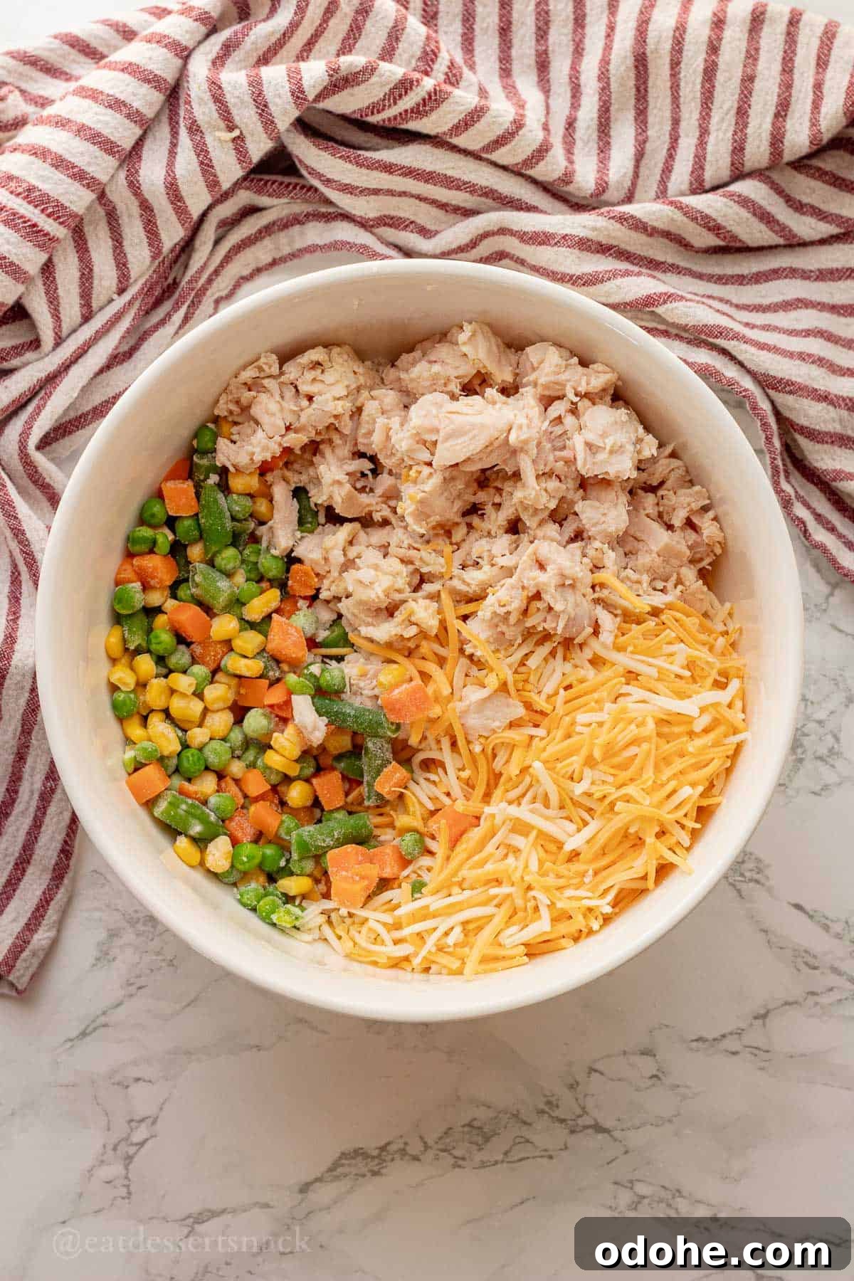 Cheesy Chicken, Rice & Veggie Casserole Recipe 5 Cheese, chicken, and frozen veggies in white bowl.
