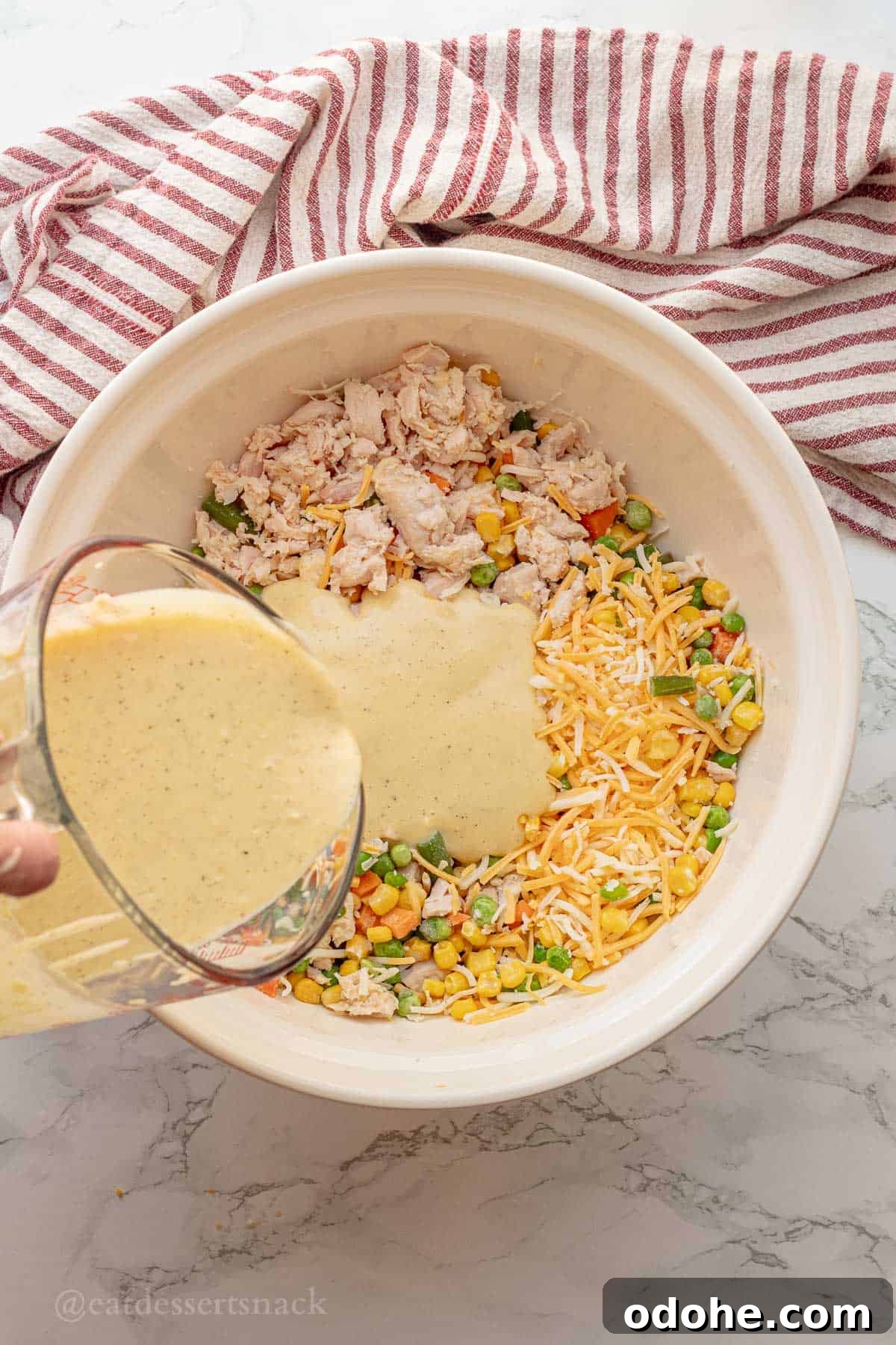 Cheesy Chicken, Rice & Veggie Casserole Recipe 7 Pouring sauce into bowl of chicken, veggies, and cheese.