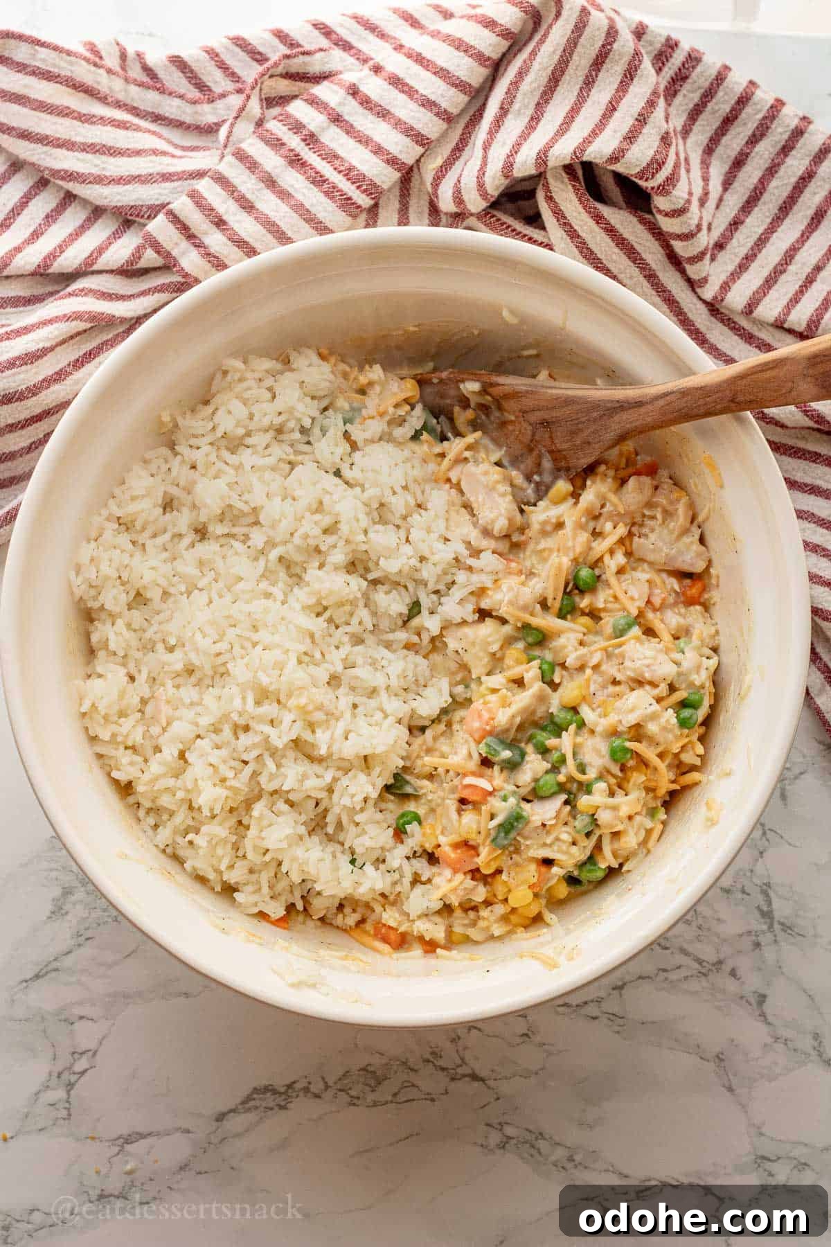 Cheesy Chicken, Rice & Veggie Casserole Recipe 8 Cooked rice, veggies, and gravy in white mixing bowl with wooden spoon.