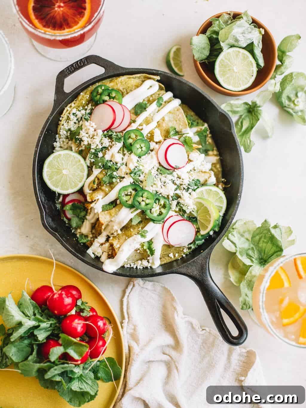 Easy Green Chicken Enchiladas Platter of green chicken enchiladas in a black cast iron skillet.