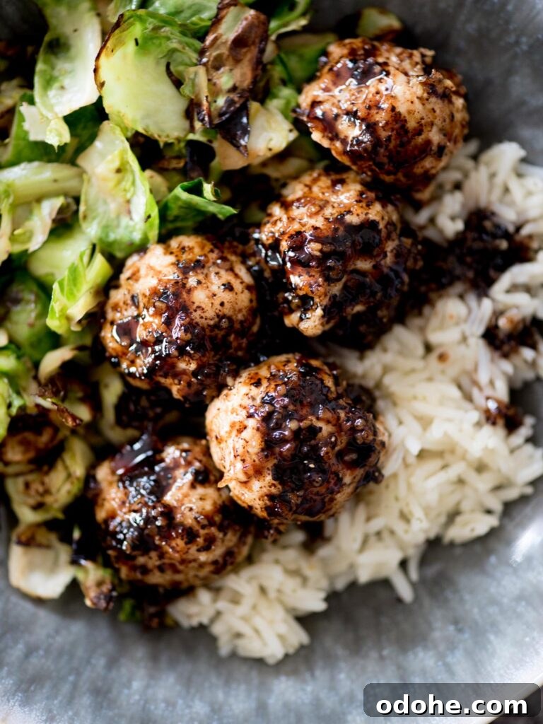 Sticky-Sauce Chicken Meatballs with Sweet Glaze 2 sticky sweet chicken meatballs in a bowl with rice and brussels sprouts