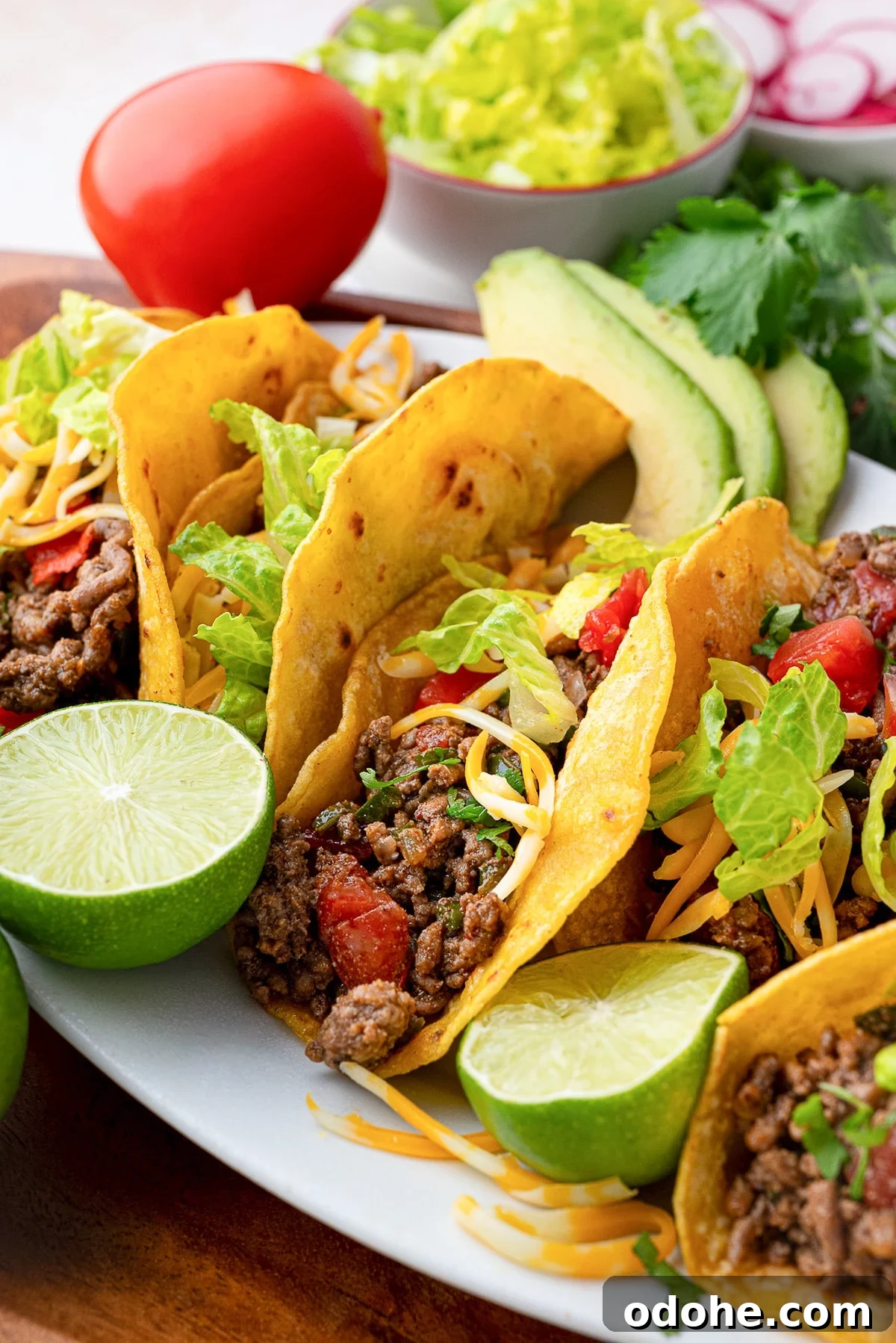 Flavorful Ground Beef Taco Meat Recipe for Authentic Tacos 6 crispy beef taco meat in shells garnished with Roma tomatoes, limes, cilantro and cheese