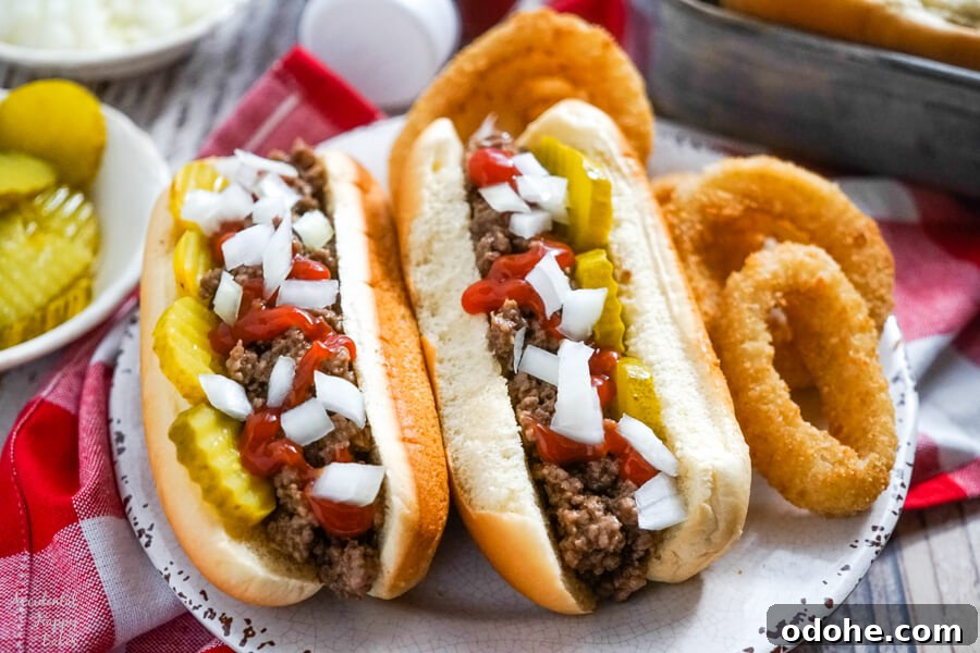 Juicy Midwestern Loose Meat Sandwich Recipe for Classic Burgers 2 Two Juicy Burgers topped with pickles, onions and ketchup on a plate with onion rings.