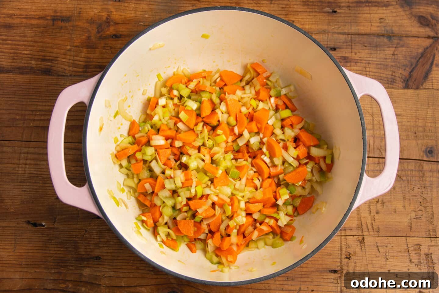 This is a picture of a large pot with chopped onion, carrot, celery and leeks.