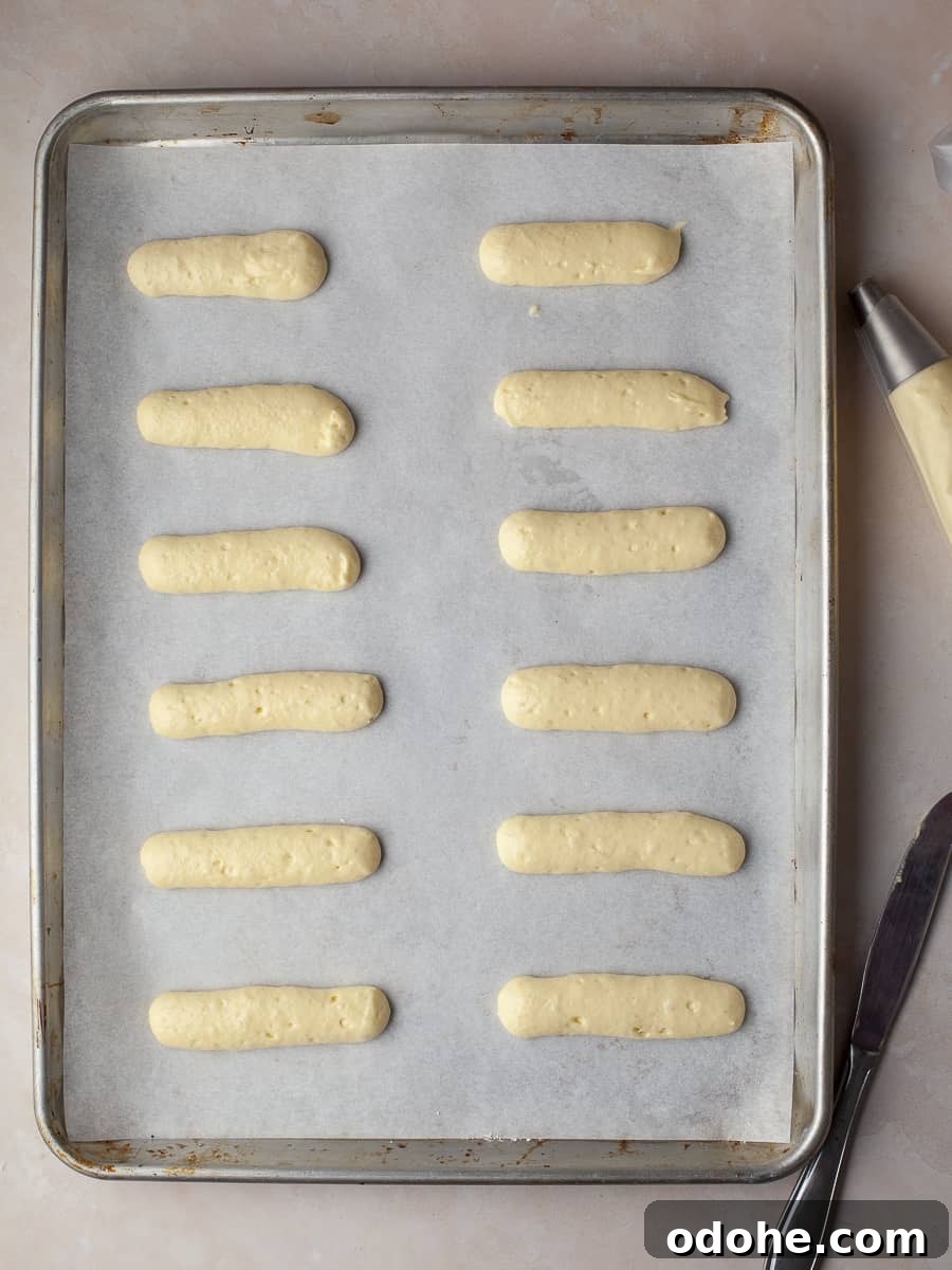 piped ladyfingers on a sheet tray