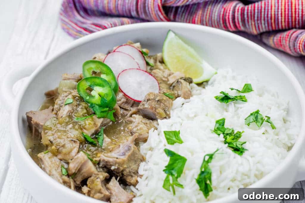 Slow Cooker Pork Chile Verde Recipe for Tender, Flavorful Pork 9 A white bowl filled with chile verde pork stew and white rice, garnished with sliced radishes, jalapenos, lime, and cilantro. A colorful cloth is in the background.