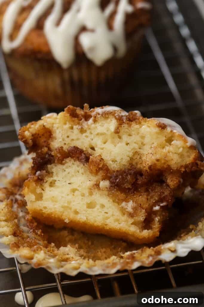 A cinnamon roll muffin sliced in half on a muffin liner