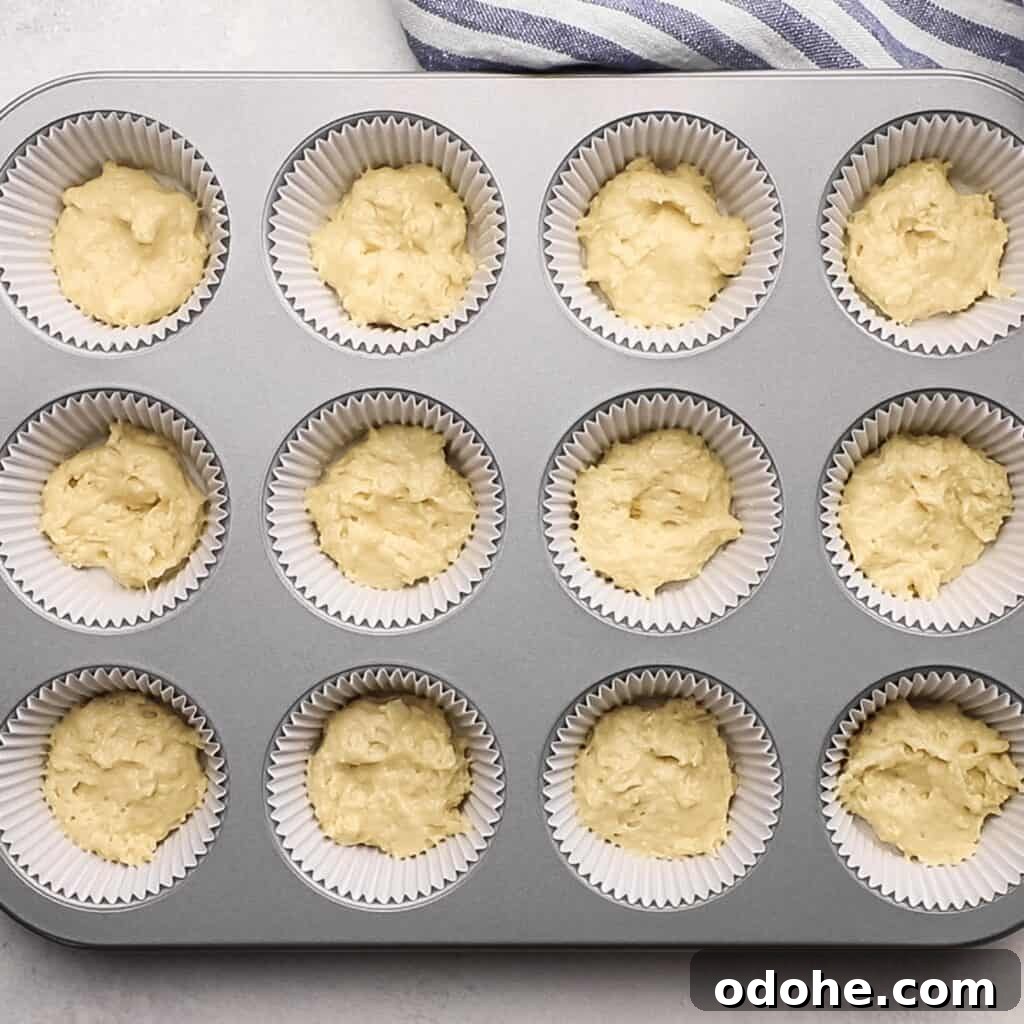 A muffin tin with a tablespoon of muffin batter in each cavity