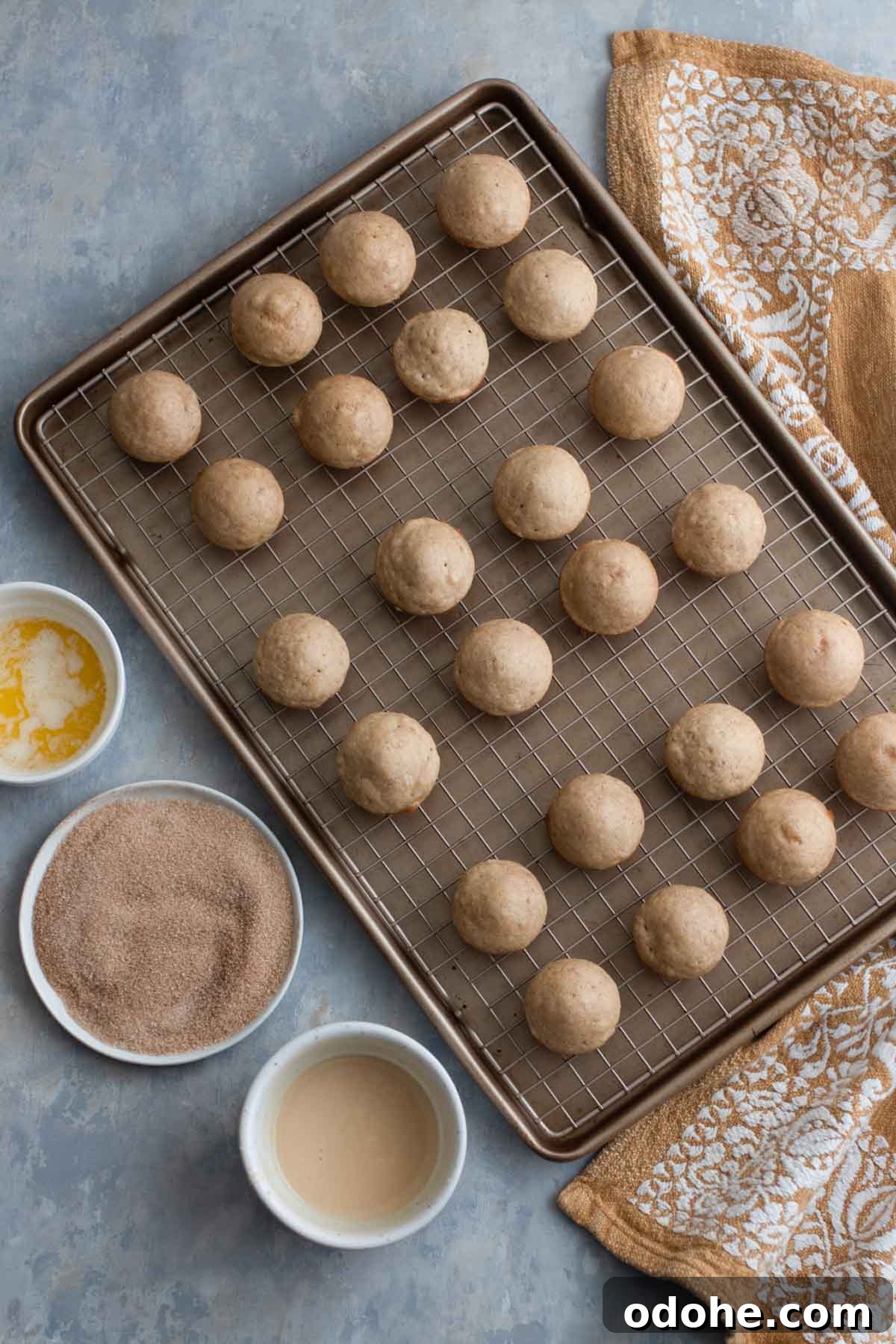 Freshly baked donut holes cooling on a baking rack.