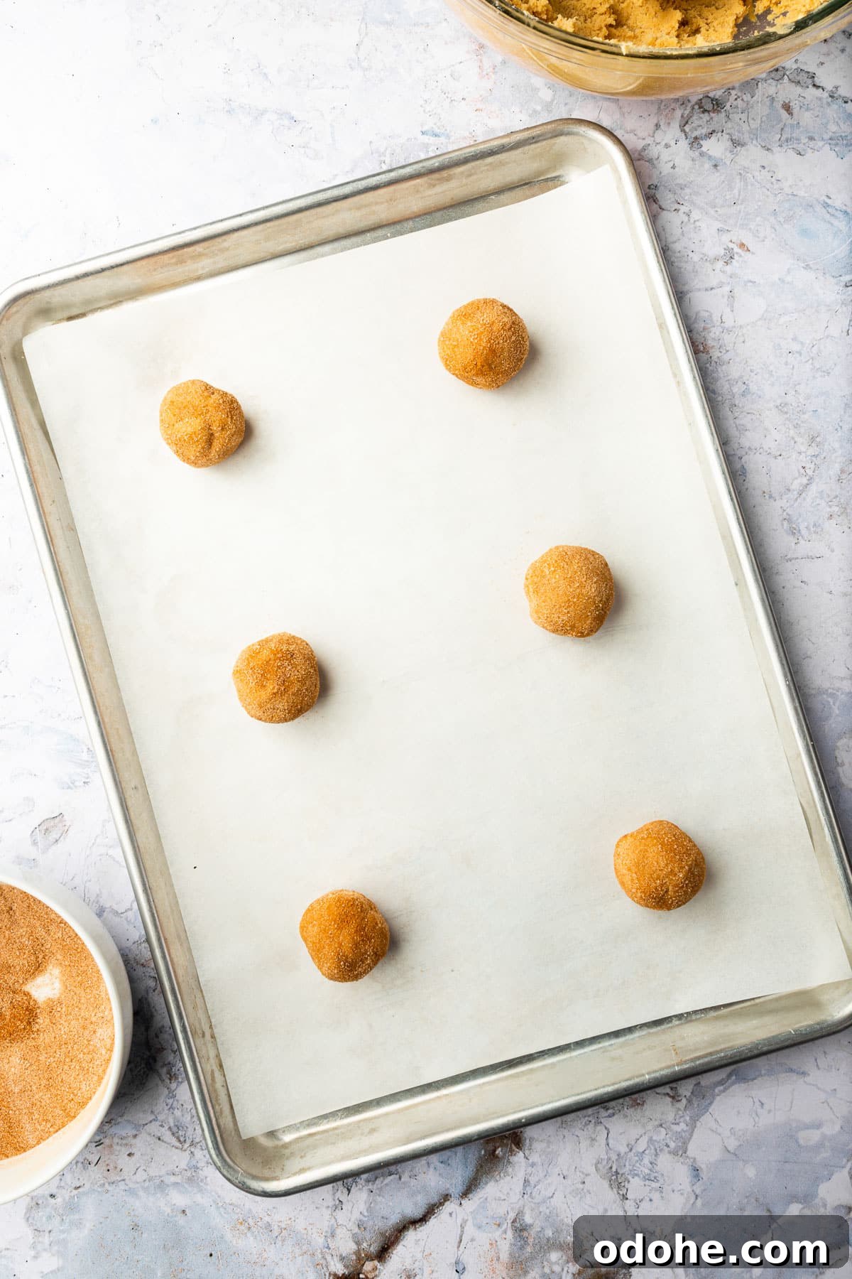 Gluten-Free Snickerdoodle Cookies Recipe: Soft, Cinnamon-Sugar Treats 11 Six gluten-free snickerdoodle cookie dough balls on a baking sheet lined with parchment paper before baking in the oven.