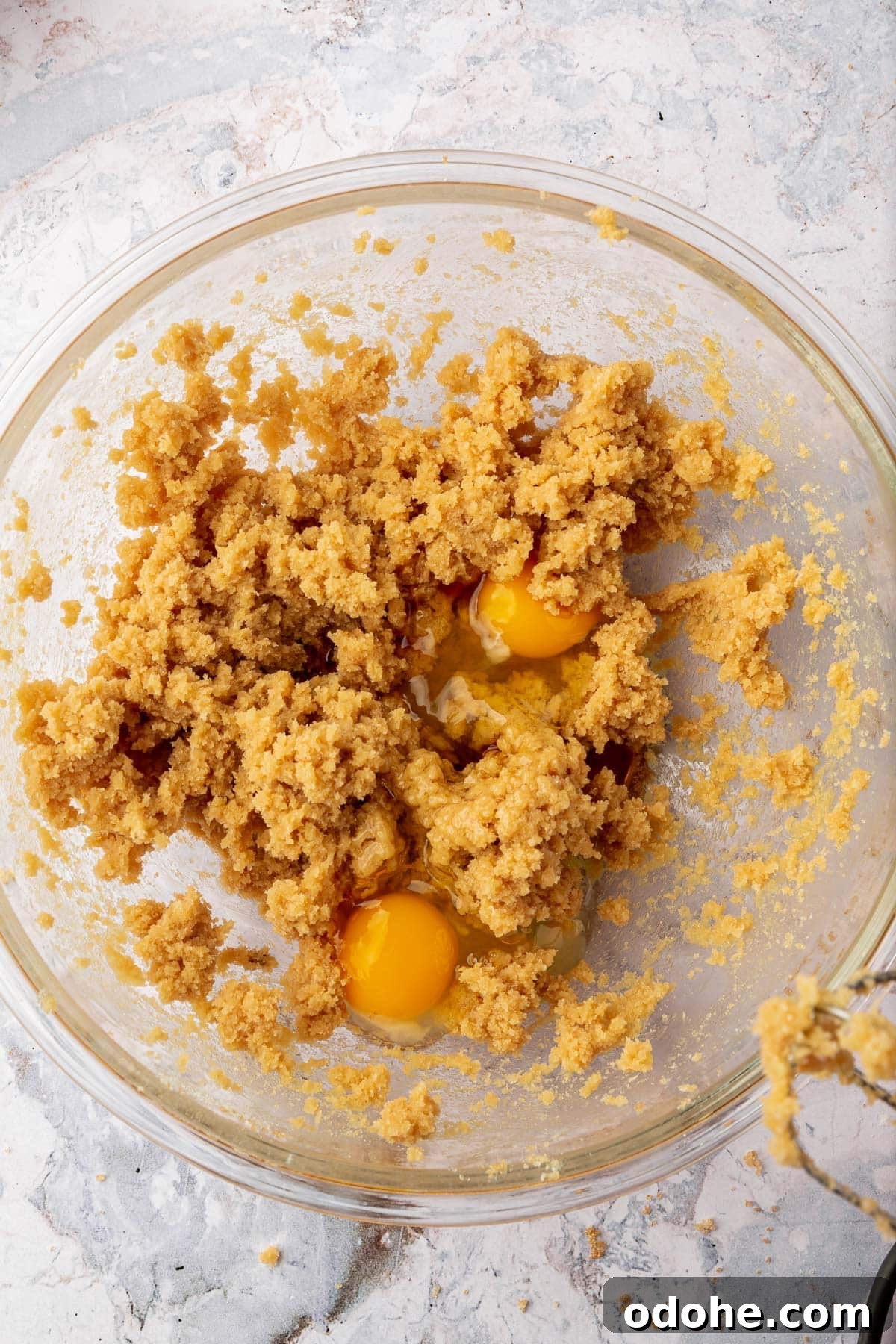Gluten-Free Snickerdoodle Cookies Recipe: Soft, Cinnamon-Sugar Treats 6 A glass mixing bowl with a creamed butter and brown sugar mixture topped with two raw eggs before mixing together.