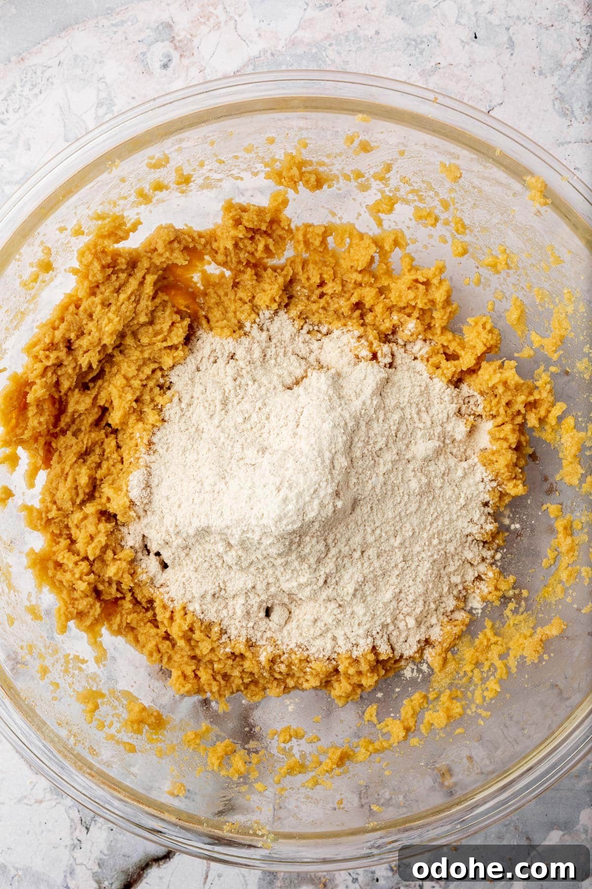 Gluten-Free Snickerdoodle Cookies Recipe: Soft, Cinnamon-Sugar Treats 7 Gluten-free flour on top of a butter and sugar mixture to make cookies in a glass mixing bowl.