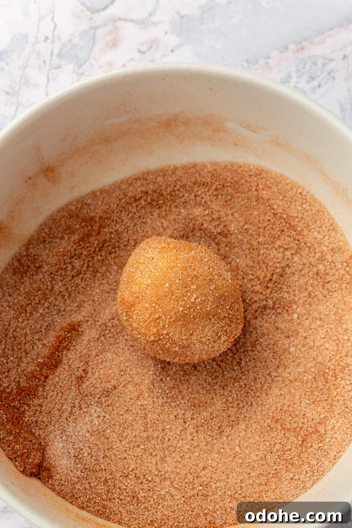 Gluten-Free Snickerdoodle Cookies Recipe: Soft, Cinnamon-Sugar Treats 10 A gluten-free snickerdoodle cookie dough ball rolled in a bowl of cinnamon sugar.