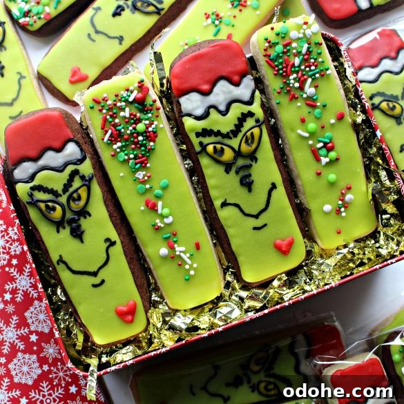 Four Decorated Grinch Cookies in a gift tin filled with shredded gold mylar.
