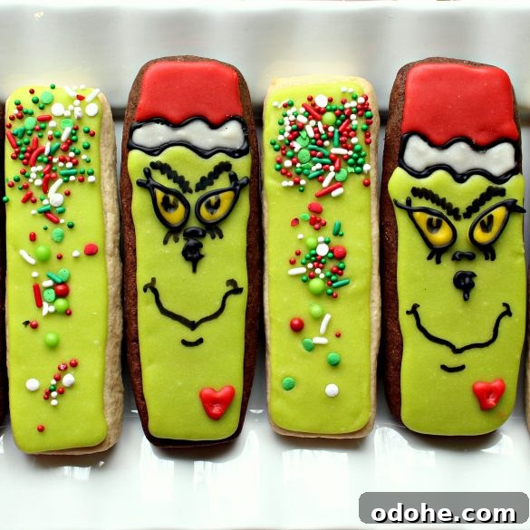 Two Grinch cookie sticks and two green sprinkled cookie sticks on a white plate.