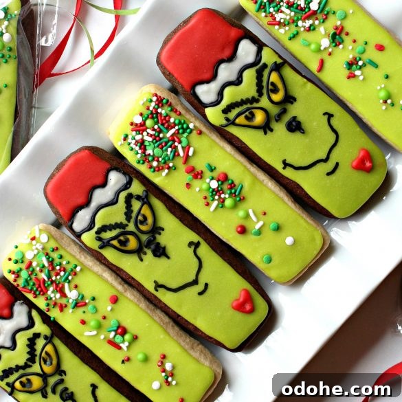 Diagonal photo of Decorated Grinch Cookies and Green Sprinkled Cookies on a white platter.