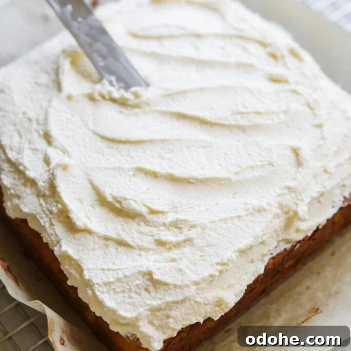 Offset spatula spreading vanilla bean mascarpone frosting on a cake.