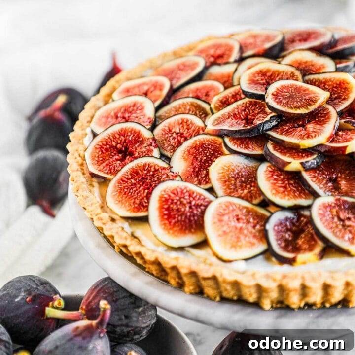 Fig tart with whipped mascarpone and honey filling on a marble serving platter.