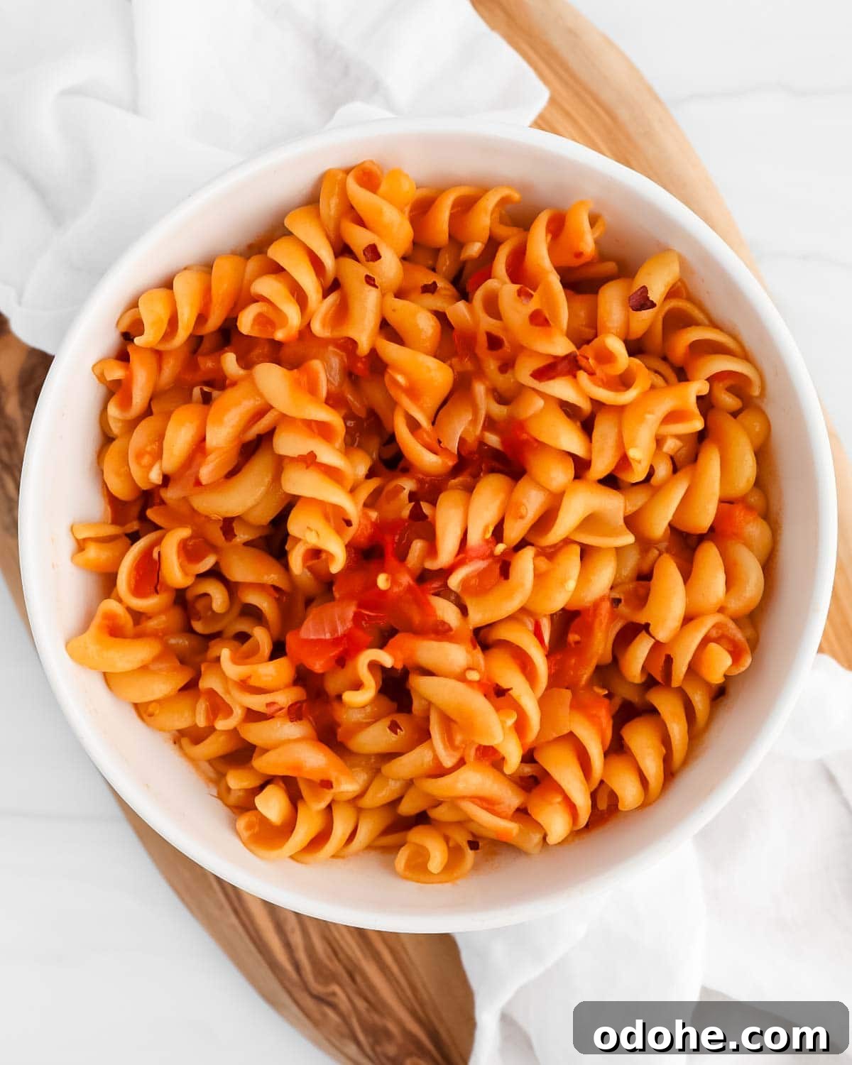 Pasta in a red sauce inside a white bowl.