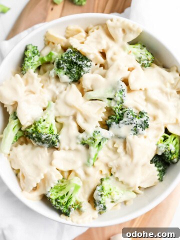 A white bowl filled with creamy bowtie pasta with broccoli in it.